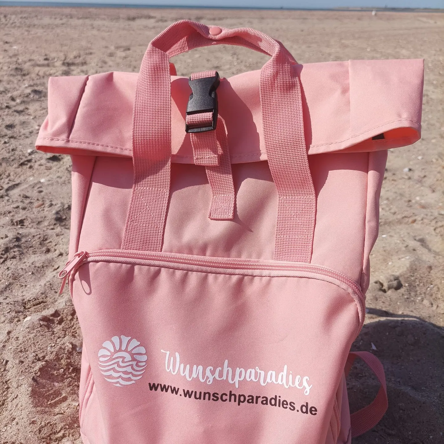 Rosa Rucksack mit Wunschparadies-Motiv am Strand